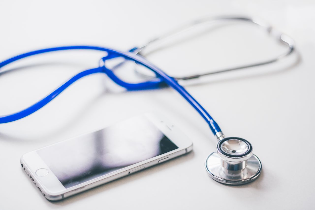 creative-01 A smartphone and blue stethoscope on a clean white surface, emphasizing modern healthcare.
