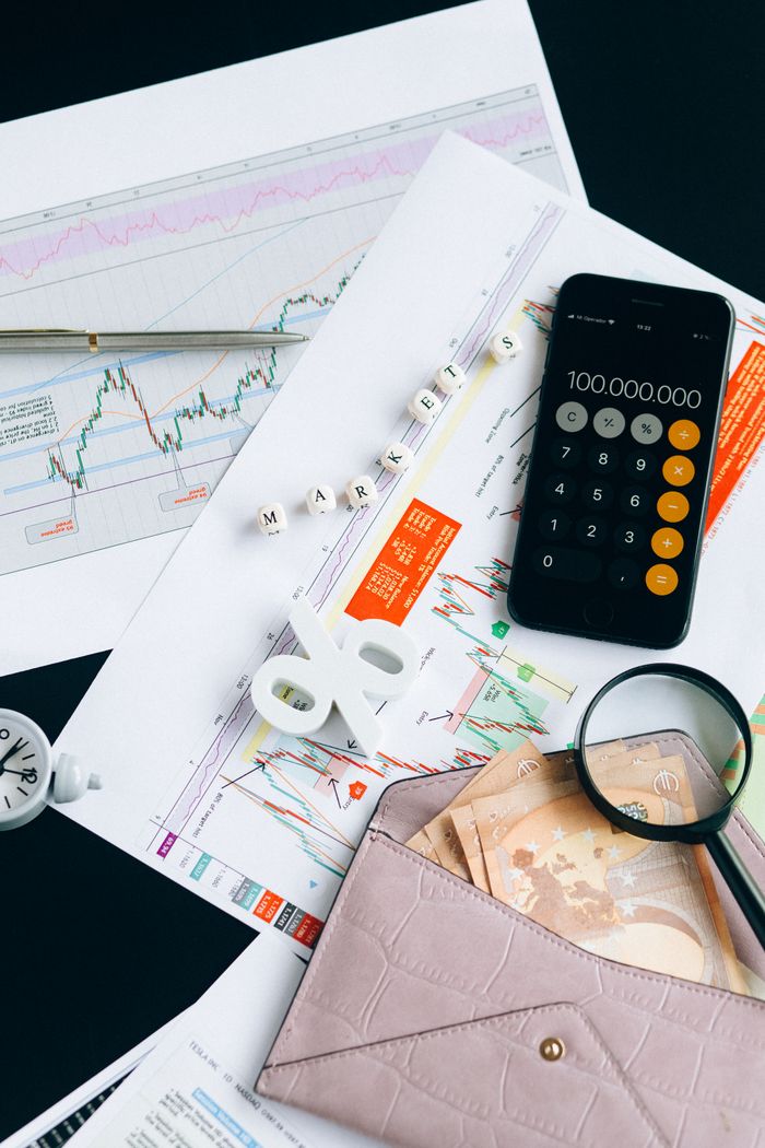 Flat lay of financial charts, smartphone calculator, and documents for market analysis.
