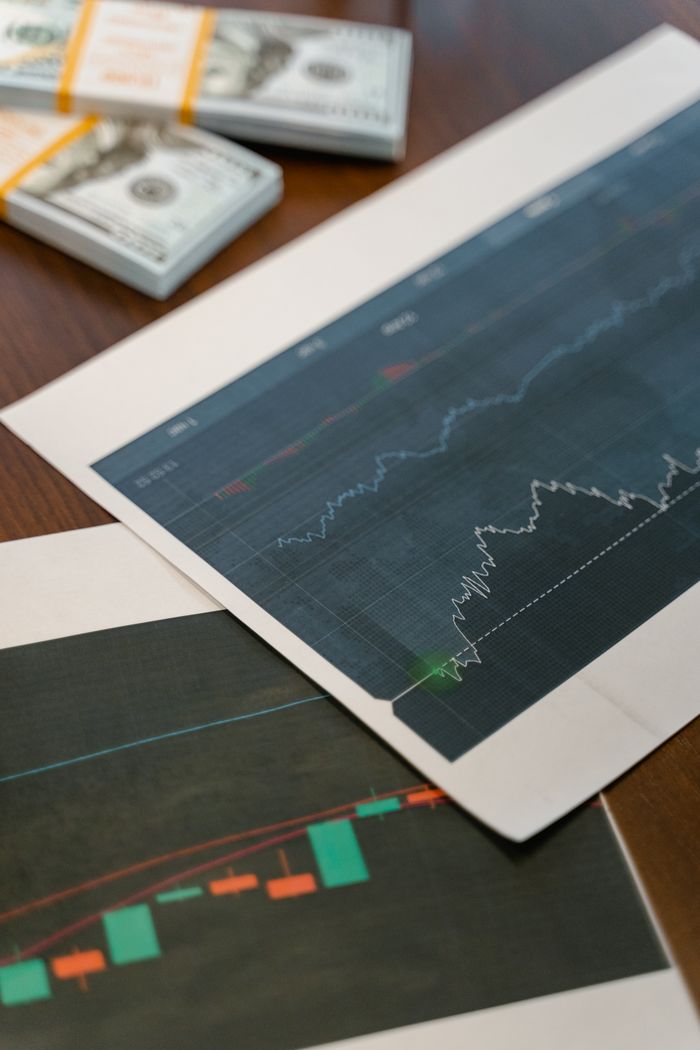 Crafting Captivating Headlines: Your awesome post title goes here Papers with financial graphs beside stacks of US dollar bills representing market analytics.