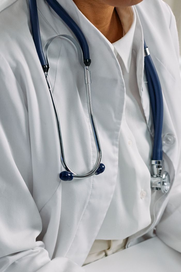 digital-01 Close-up of a healthcare professional's stethoscope draped around a white coat, symbolizing clinical care.