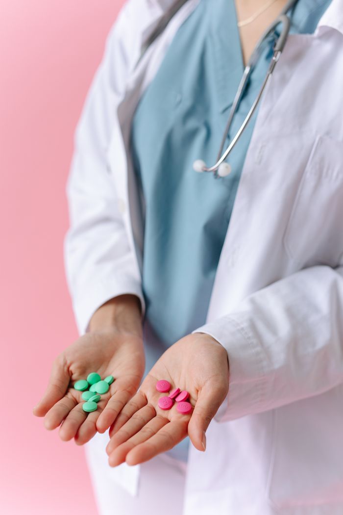 mobile-01 Medical professional displaying colorful pills in hands on a pink background.
